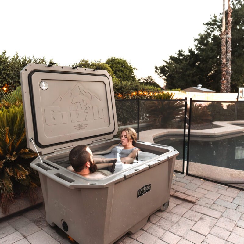 A photo of a man and a woman tandem cold plunging together outside in a Desert Plunge 450 Wide cold plunge.