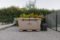 Picture of The Wide Grizzly 450 Cold Plunge Tub sitting on a patio made of brick pavers. The cold plunge lid is closed and latched, and the chiller is attached. There is a hedge behind the tub with some palm-like foliage.